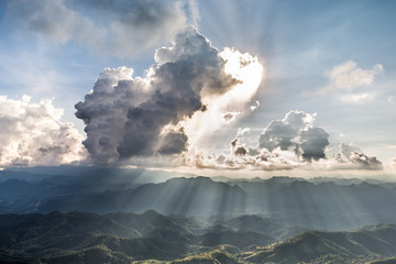 Golden light rays from clouds shining down to mountains. Sun rays over valley. Sun rays over hill....