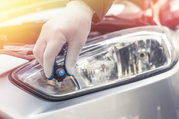 the mechanic replaces the halogen bulbs in the headlights in the car