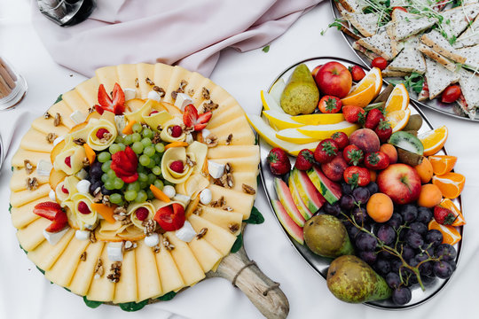 photo of a cheese plate and a fruits plate on a table