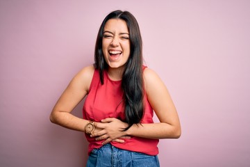 Young brunette woman wearing casual summer shirt over pink isolated background smiling and laughing hard out loud because funny crazy joke with hands on body.