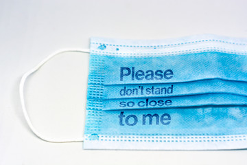 blue surgical mask with the indication to maintain social distancing and not to stay so close. Covid-19 pandemic and social distancing to prevent the spread of the virus