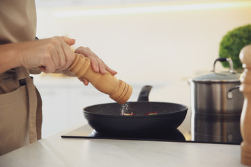 Woman cooking on stove in kitchen, closeup