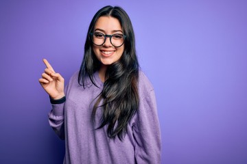Young brunette woman wearing glasses over purple isolated background with a big smile on face,...