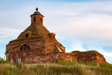 an old half-forgotten Church in a clearing with grass against the sky