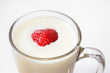 red fresh ripe sweet strawberries floating in cow's milk poured in a clear glass glass on a white background Breakfast place for text
