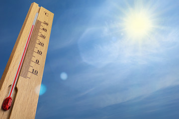 Wooden thermometer with red measuring liquid showing 40 degrees Celsius on a sunny day.