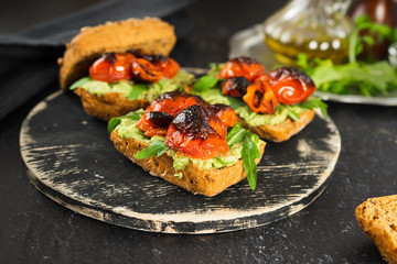 Close up of delicious vegan sandwiches with mashed avocado, roasted tomatoes and arugula