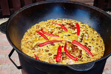 National Uzbek dish pilaf, pilaw, plov, rice with meat in big pan. Cooking process in a cauldron on...