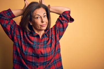 Fototapeta na wymiar Middle age beautiful woman wearing casual shirt standing over isolated yellow background Doing bunny ears gesture with hands palms looking cynical and skeptical. Easter rabbit concept.