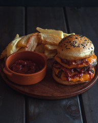 hamburger with french fries, with cheddar cheese, bacon, tomato sauce and mayonnaise on wooden background