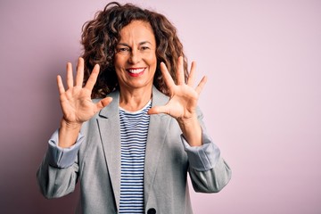 Middle age beautiful businesswoman wearing elegant jacket over isolated pink background showing and pointing up with fingers number ten while smiling confident and happy.