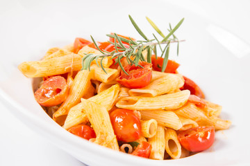 Penne with tomatoes, garlic and mozzarella decorated with rosemary twig, on a white background