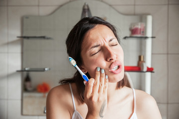 Tooth Pain And Dentistry. Beautiful Young Woman Suffering From Terrible Strong Teeth Pain, Touching Cheek With Hand. Female Feeling Painful Toothache. Dental Care And Health Concept.teeth cleaning