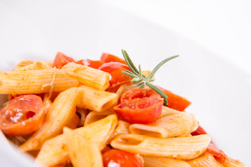 Penne with tomatoes, garlic and mozzarella decorated with rosemary twig, on a white background