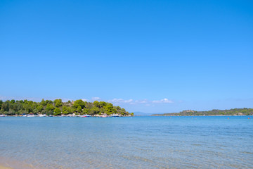 Landscape of turquoise water with green hill in the background and blue sky during summer day