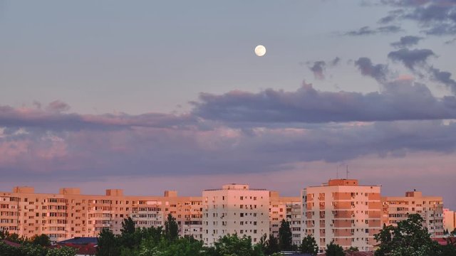 Moon rise over apartment buildings at sunset - time lapse. Cityscape in a residential neighborhood of Bucharest, Romania.