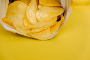 Potato chips in a pack on a yellow background. Copy, empty space for text