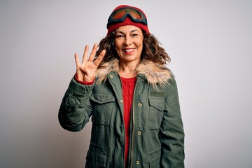 Middle age skier woman wearing snow sportswear and ski goggles over white background showing and pointing up with fingers number four while smiling confident and happy.