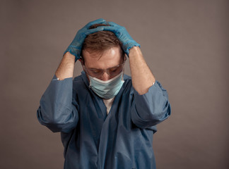 Male doctor feeling exhausted after long shift treating coronavirus infected patients at hospital
