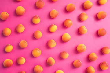 Fresh apricots scattered over pink background