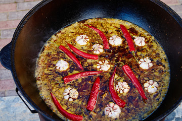 National Uzbek dish pilaf, pilaw, plov, rice with meat in big pan. Cooking process in a cauldron on...