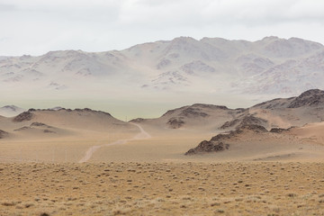 Mongolia landscape. Winding dirt road through lush rolling hills of Central Mongolian steppe. Mongolian Altai