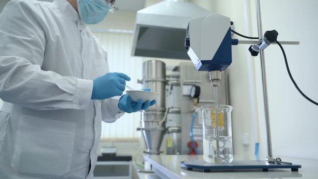 man scientist male researcher mixing reagents in beaker spbas . automatical testing chemical mixing stirrer. concept experiment, analyzing, coronavirus. biotechnology chemist
