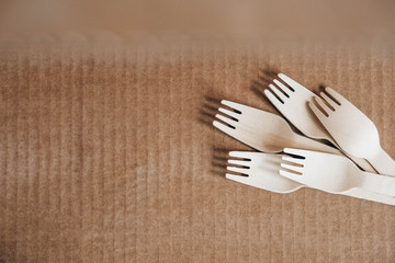 Wooden forks on a cardboard background. Eco friendly disposable tableware. Top view. Copy, empty space for text