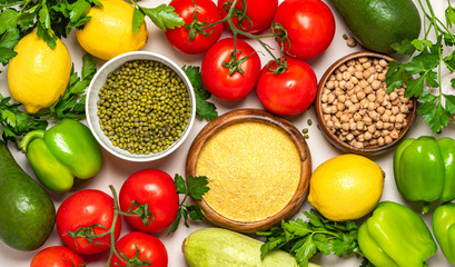 Food background. Various vegetables, chickpeas, mung bean and polenta top view. Avocado, pepper, tomatoes, lemons, polenta, chickpeas and mung bean flat lay. Vegetarian and vegan food, arabic cuisine