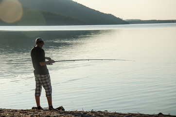 fisherman fishing with a fishing rod at sunset