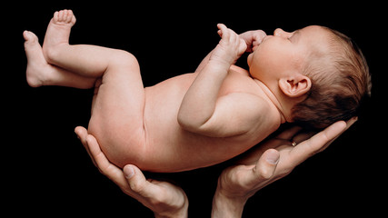 dad holds a newborn baby on a black background sleeps cute