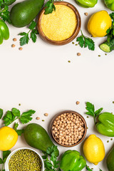 Frame of green and yellow vegetables, cereals and legumes on a white background, top view. Avocado, pepper, polenta, chickpeas and mung bean flat lay, copy space, banner. Vegetarian and vegan food