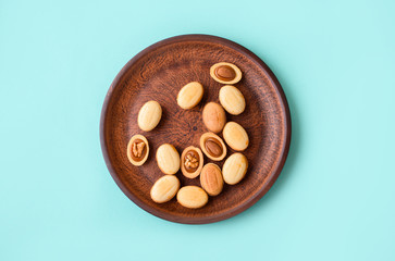 Homemade nuts with condensed milk, chocolate inside, walnuts and almonds. Dessert to tea on a plate on a light blue background.