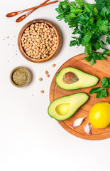 Chickpeas, avocado, cumin, lemon and cilantro on a light background, top view, flat lay. Ingredients for making hummus with avocado.