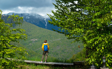 Woman in bright clothes makes photos using a smartphone in front of the mountains