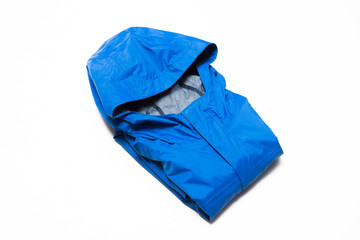 Folded blue zipper windbreaker jacket, rain proof and waterproof hiking Gore-Tex jacket hoodie. Track jacket sport nylon full zip isolated on white. Folded clothes. Outer layer garment for travel.