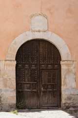 Fototapeta na wymiar old wooden door with round stone arch and stone cartouche in a front building
