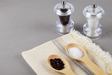 Wooden spoons on a linen napkin with pepper and sea salt, copy spase
