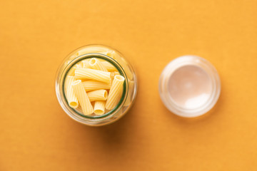 Canning jar filled with rigatoni pasta on orange background and soft Swabian