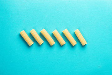 Rigatonis arranged in a row with blue background and soft light