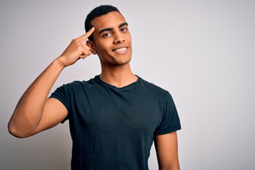 Young handsome african american man wearing casual t-shirt standing over white background Smiling pointing to head with one finger, great idea or thought, good memory