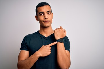 Young handsome african american man wearing casual t-shirt standing over white background In hurry...