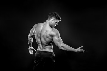 Naklejka premium Sexy young athlete posing on a black background in the Studio. Fitness, bodybuilding, black and white