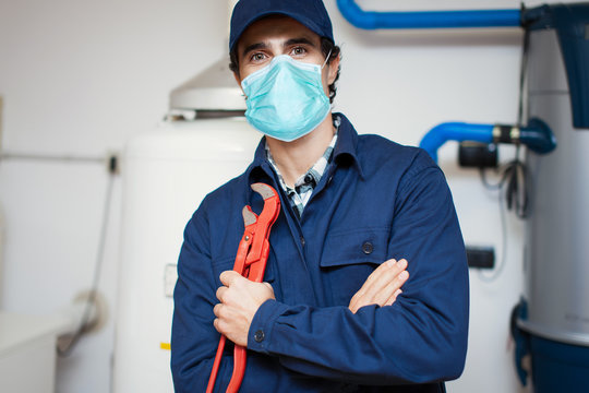 Smiling technician repairing an hot-water heater wearing a mask, coronavirus concept