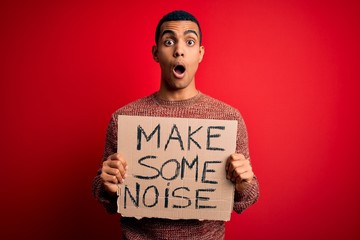 Handsome african american activist man protesting holding banner with make noise message scared in...