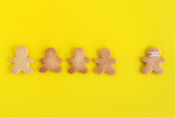 Homemade shortbread cookies with white glaze on yellow background, top view. Crowd of people and one man in face mask.
