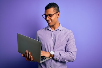 Young handsome african american business man working using laptop over purple background with a happy face standing and smiling with a confident smile showing teeth
