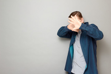 Portrait of man stretching palms to camera and covering his face