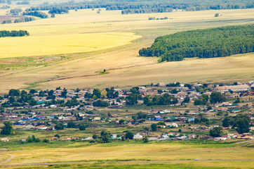 Fototapeta premium village in the mountains aerial view among fields and mountains and clouds by the lake