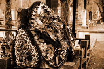 wreaths of artificial branches and flowers on a grave in a cemetery. Sepia cemetery photo. respect for the deceased by relatives